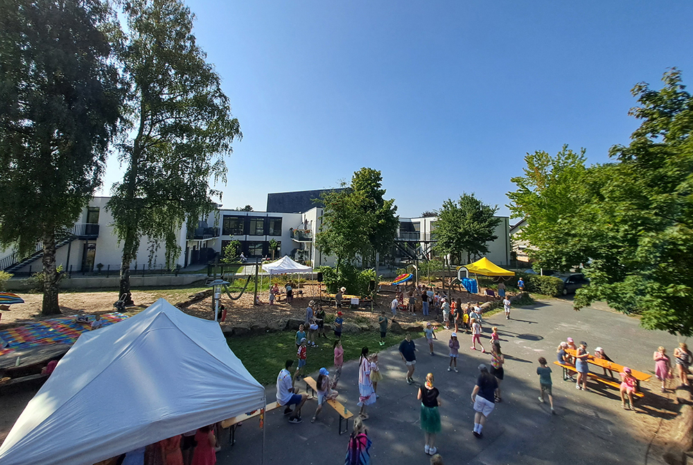 Foto vom Schulhof von oben der Ferienbetreuung mit spielenden Kindern